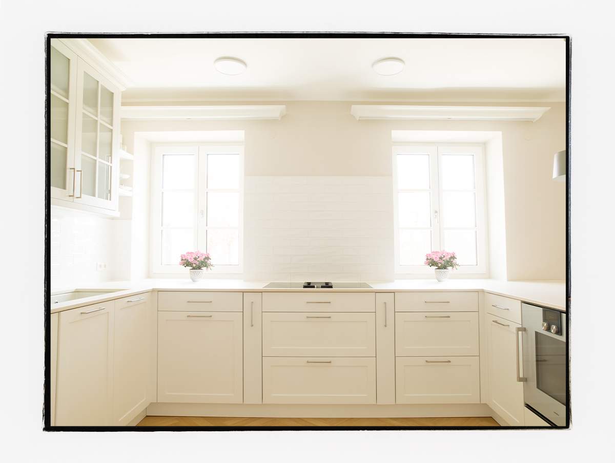 Küche im klassischen Landhaus-Stil mit weißen Küchenschränken und einer beigen Dekton-Arbeitsplatte